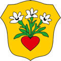 Wappen der Großgemeinde Nickelsdorf. Gelbes Wappen in Schildform. Darauf findet sich ein rotes Herz aus dem drei weiße Blumen spriesen.