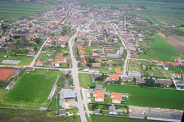 Luftbild von Nickelsdorf mit Blickrichtung Südosten, im Vordergrund die Obere Hauptstraße mit dem Sportplatz, im Hintergrund das Ortszentrum